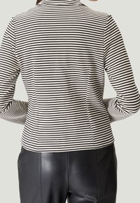 Veste à rayures noires et blanches à manches longues, coupe ajustée, tissu lisse et coutures structurées aux épaules, vue de dos.