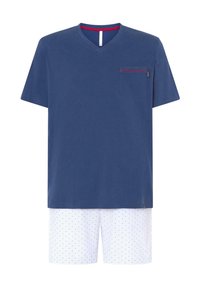 Camiseta de algodón azul marino con cuello en V y bolsillo en el pecho; combinada con pantalones cortos blancos con rayas azules y pequeños puntos rojos.