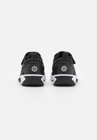 Black athletic shoes with a mesh upper, white accents, and a perforated texture. Features a logo on the heel and a contrasting sole.