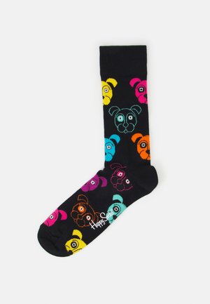 Black socks featuring colorful, cartoonish dog faces in pink, yellow, orange, blue, and purple. Includes logo “Happy Socks” in white.
