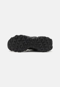 Suola di sneaker in gomma nera con un motivo di battistrada testurizzato caratterizzato da forme ondulate per una migliore aderenza e trazione.