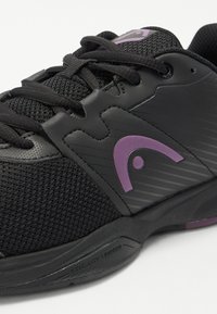 Black athletic shoe featuring mesh and synthetic upper, purple accents, and textured design elements. Includes black laces and rubber sole.