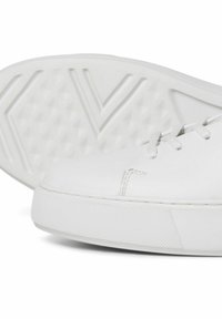 Basket blanc avec une tige en cuir lisse, des lacets et une semelle en caoutchouc texturée avec un motif en losanges pour une meilleure adhérence.