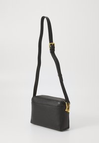 Black leather crossbody bag with a rectangular shape, textured surface, gold hardware, and an adjustable strap. Zipper closure at the top.