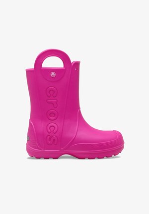 Pink waterproof rubber boot with raised edge, rounded toe, textured sole, and "crocs" logo on the side. Features side handle for easy wear.