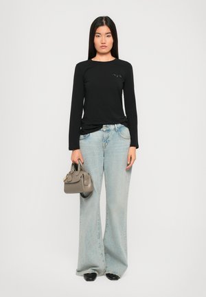 Black long-sleeve T-shirt with a minimalist design, light blue wide-leg jeans, and a small grey handbag. The outfit features a casual style.