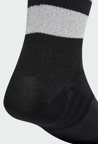 Calcetín negro con rayas horizontales grises, hecho de un tejido texturizado. Presenta una puntera reforzada y un acabado suave, diseñado para la comodidad.