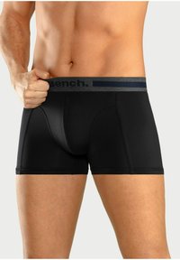 Schwarze Baumwollboxershorts mit taillierter Passform, ausgestattet mit einem grauen elastischen Bund, der das Logo "Bench." in einer kontrastierenden Farbe trägt.