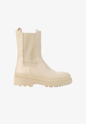 Beige leren enkellaars met grove zool, elastisch zijpaneel, trek-lussen en een geperste "Christian Dior Paris" branding aan de zijkant.