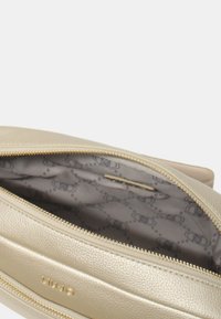 Borsa in pelle dorata con chiusura a zip. Interno con fodera stampata e un design sottile. Texture liscia e forma slanciata.