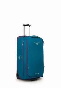 Maleta grande color teal con un acento púrpura, que cuenta con un mango retráctil, cremalleras y un logo de Osprey en la parte frontal. Tejido texturizado.