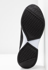 Schwarze Sportlaufschuhsohle mit einem strukturierten Gummi-Griff, in der Mitte mit einem weißen Akzent und einem strukturierten schwarzen Obermaterial.