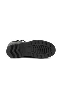 Semelle de chaussure en caoutchouc noir avec un motif de bande de roulement en zigzag, dotée d'un marquage en relief et de détails de taille, texturée avec une finition lisse.
