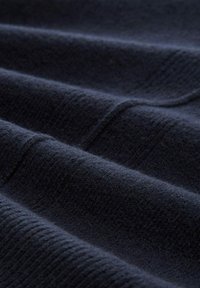 Marineblaue Stoff mit einer weichen, strukturierten Oberfläche, die feine Rillen und Falten aufweist, wodurch Tiefe und Lichtvariation entstehen.