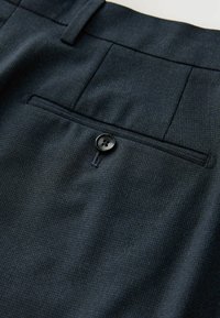 Dark, textured fabric trousers with a subtle pattern, featuring a single back pocket and a black button closure.