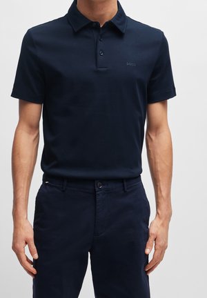 Navyblaue Polohemd aus weichem, elastischem Material. Verfügt über einen kragenförmigen Ausschnitt, eine Drei-Knopfleiste und ein dezentes Logo auf der Brust.