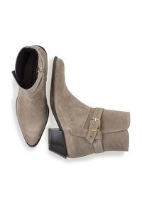 Bottines en suède gris avec orteils pointus, sangle décorative à boucle, talons blocs bas et détail de zip exposé. Finition texturée.