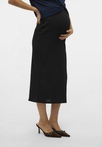 Zwarte rok tot de knie, geribbelde textuur, aansluitend ontwerp met een rechte snit, gecombineerd met bruin stilettohakken met decoratieve accenten.