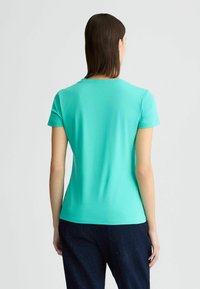 Lichtblauwe korte mouwen t-shirt gemaakt van zachte stof, met een ronde hals en een getailleerd ontwerp, vanachter weergegeven.