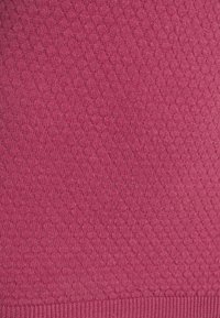 Tissu tricoté texturé de couleur rose profond, présentant un motif en losange et un ourlet côtelé. Matière douce avec une légère brillance.