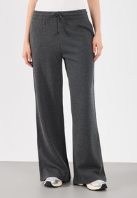 Calças de fato largas e cinzentas, feitas de um tecido suave e respirável. Apresenta uma cintura elástica com cordão para um ajuste ajustável.