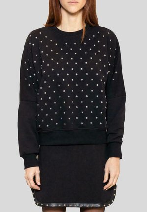 Felpa nera con un design a motivo di borchie argentate, con maniche lunghe e scollatura rotonda, abbinata a una gonna nera coordinata.