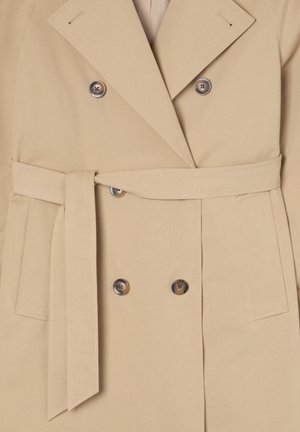 Beżowy dwurzędowy płaszcz z paskiem, wykonany z miękkiego materiału, z dużymi guzikami i kołnierzem z klapami, z bocznymi kieszeniami.