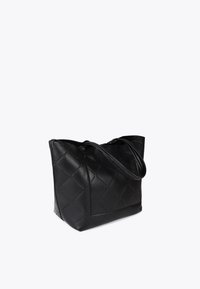 Schwarze Leder-Tote mit gesteppter Oberfläche und doppelten Griffen, in einem Winkel vor einem schlichten Hintergrund platziert.