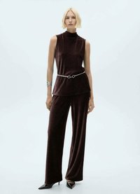 Bordeaux ribbed mouwloos top met hoge hals, gecombineerd met een broek met wijde pijpen, accentueert met een zilveren riem en gedragen met puntige zwarte hakken.