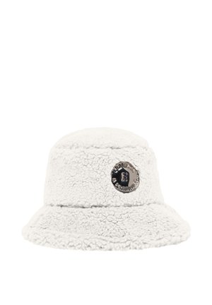 White fluffy bucket hat with a round metallic logo patch on the front displaying text and a small graphic in the center.