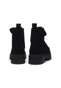 Botine negre din suede cu o talpă chunky din cauciuc negru, dotate cu tab-uri pentru prindere în spate și o textură netedă. Fără embellishments vizibile.