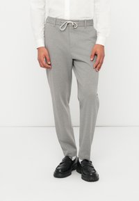 Γκρι παντελόνια φόρμας με σούρα στη μέση, με απαλή υφή και στενές μπατζάκια, συνδυασμένα με μαύρα μοκασίνια.