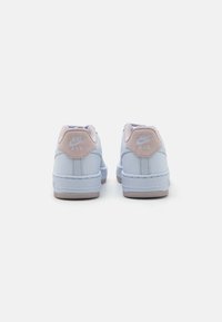 Zili zili Nike Air sporta apavi ar teksturētu ādas virsmu, gaiši rozā zamša akcentiem uz papēža un balto gumijas zoli.