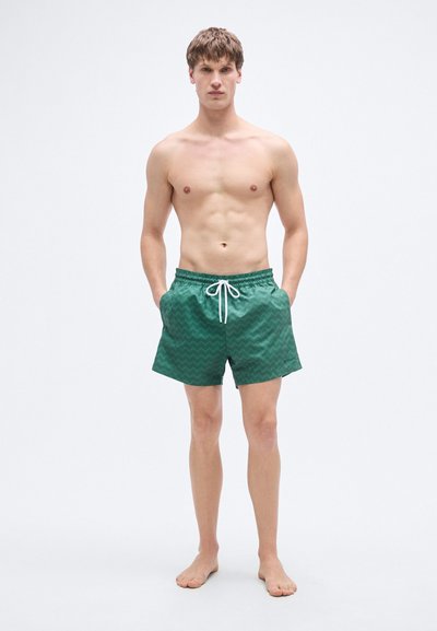 Πράσινα μαγιό με σχέδιο ζιγκ-ζαγκ, κατασκευασμένα από ελαφρύ υλικό, με ελαστική μέση και κορδόνι.