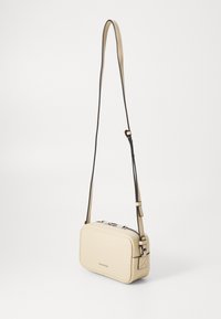 Borsa a tracolla beige in pelle testurizzata, forma rettangolare, tracolla regolabile, chiusura con cerniera e dettagli hardware minimalisti.