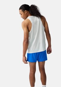 Sporty tank top i lysegrå mesh stof, parret med blå shorts. Designet har rund halsudskæring og en afslappet pasform for komfort.