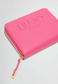 Portafoglio sintetico rosa con finitura strutturata, logo impresso, dettaglio della cerniera in oro e linguetta per la chiusura lampo. Forma rettangolare compatta.