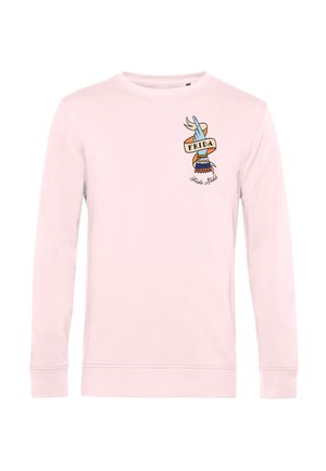 Maglietta rosa chiaro a maniche lunghe con grafica di una mano blu avvolta da un nastro arancione con la scritta "FRIDA" e testo in corsivo "Frida Kahlo" sotto.