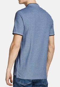 Polo shirt azzurro chiaro a maniche corte caratterizzato da un colore uniforme con una sottile trama, dettagli neri sul colletto e sulle maniche, e un orlo dritto.