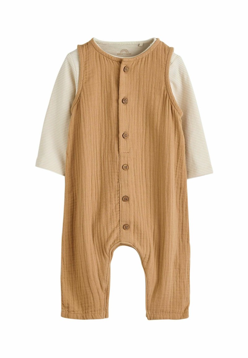 Brun ribbet bomulds romper med knaplukning, ærmeløs design og en langærmet cremet stribet skjorte under. Har rund hals.