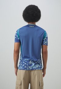 Maglietta atletica a maniche corte, traspirante, con una combinazione di colori blu e verde acqua, caratterizzata da motivi astratti e dettagli testurizzati sulle maniche.