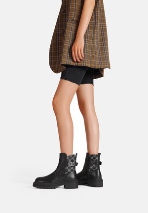 Stivaletti alla caviglia in pelle nera con suola spessa, dotati di minuteria decorativa e di un accento in tessuto decorato sul tallone.