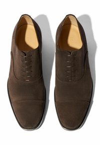 Scarpe eleganti in suede marrone con finitura liscia, dotate di punte arrotondate, sei paia di fori per i lacci e un design minimale senza decorazioni.