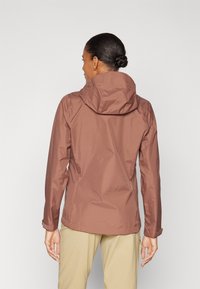 Chaqueta impermeable marrón con capucha ajustada, mangas largas y puños ajustables. Textura suave, ligera, ideal para llevar al aire libre.