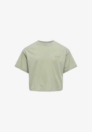 T-shirt court en coton vert clair avec un col rond. Présente un petit design de cœur doré avec des rayons de soleil sur la poitrine gauche.