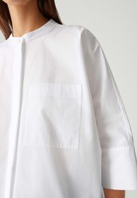 Witte, collared shirt met knoopsluiting en een borstzak. Gemaakt van soepel stof, met mouwen van 3/4 lengte en een comfortabele pasvorm.