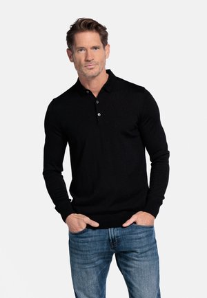 Zwarte lange mouwen polo shirt met een kraag, voorzien van een drieknoopsluiting en geribbelde manchetten, gecombineerd met blauwe jeans.