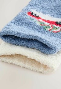 Pereche de șosete pufoase, blănoase, în nuanțe de albastru deschis și crem. Șoseta albastră are un design colorat. Material moale, cu o textură pufoasă.