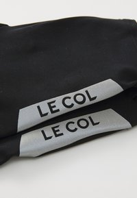 Sorte cykling armvarmere med reflekterende sølvdetaljer. Har iøjnefaldende "LE COL" branding i sort på de reflekterende paneler.