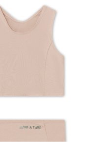 Lyse rosa ermeløs crop top laget av myk, elastisk stoff; har rund hals og en subtil logo i grønt på båndet.